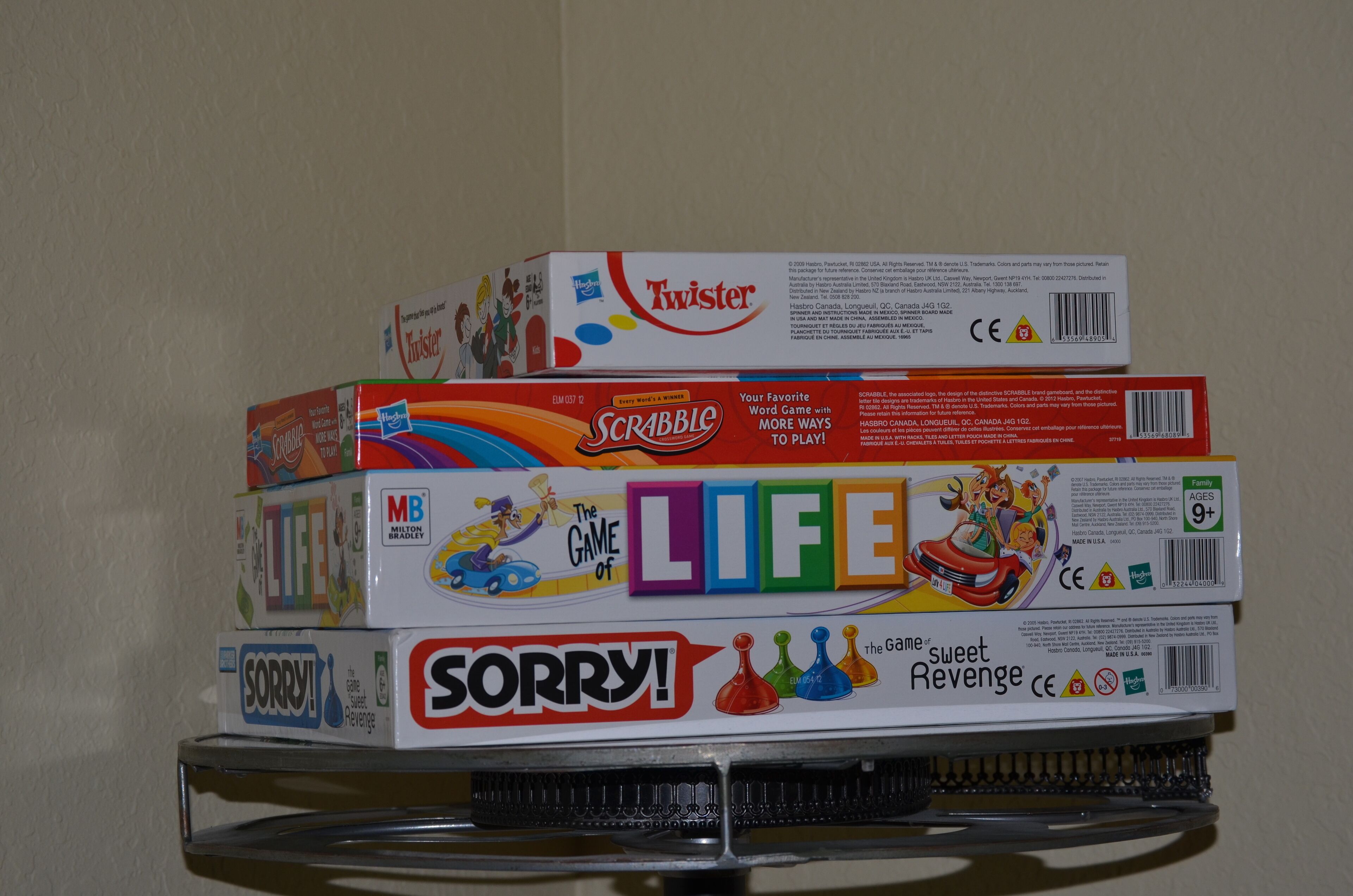 Eine Reihe Brettspiele, darunter Scrabble, Das Spiel des Lebens und Sorry!, stehen auf einem Regal.