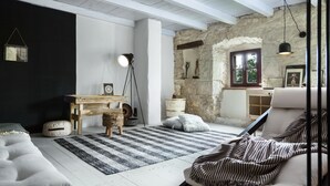 Ein gemütliches Wohnzimmer mit Steinwand, Holztisch, Sofa und einem Streifen Teppich.