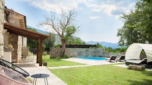 Ein Garten mit Schwimmbad, Sitzgelegenheit im Freien und einer überdachten Grillstelle.