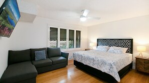 Cozy retreat with a large bed, sofa, and ceiling fan.