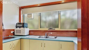 Une cuisine avec une fenêtre, un évier et un four à micro-ondes.