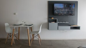 A modern dining area with a table and chairs, a mounted TV, and built-in shelving.