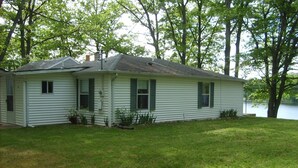 A single-story house with a sloped roof, a front porch, and a small front yard. - Quiet Cottage On The Lake (delton)