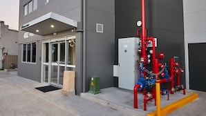 A modern building with a grey facade, a glass entrance, and visible fire safety equipment. - East Maitland Executive Apartments (East Maitland)
