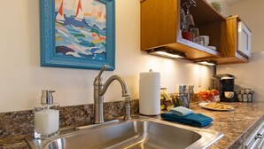 Una cocina moderna con pileta de acero inoxidable, encimera de granito y muebles de madera.