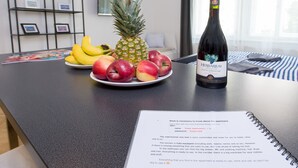 A kitchen counter with a bottle of wine, a plate of fruit, and a notebook. - Black and White , Wifi and Parking free (Praha 3)