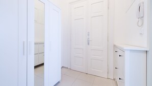 A hallway with white doors, a phone on the wall, and a cabinet with drawers. - Black and White , Wifi and Parking free (Praha 3)