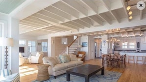 A spacious living room with a large sofa, a coffee table, and a staircase leading to another level. - Beachfront Property on Private Moody Beach (Wells)