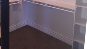Um closet espaçoso com prateleiras abertas, uma barra para pendurar roupas e um espaço embutido para sapatos.