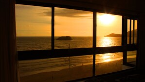 Vista del océano a través de una ventana con un atardecer.