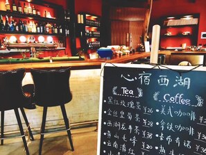 A bar area with a chalkboard menu listing tea and coffee prices.