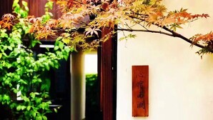 Ein traditioneller japanischer Garten mit einem Kiesweg, einem hölzernen Schild und einer Steintorii.