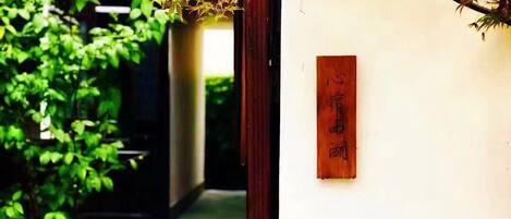 A traditional Japanese garden with a stone pathway, a wooden sign, and a stone lantern.