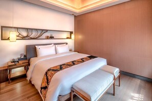 A modern hotel room with a large bed, a bedside table, a nightstand, and a decorative wall piece above the bed.
