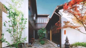Ein traditioneller japanischer Innenhof mit Steinwegen, Holzbauten und einem Steinglaternen.
