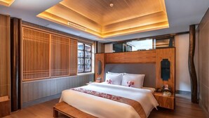 Ein modernes Hotelzimmer mit einem hölzernen Bett, einem Nachttisch, einem großen Fenster mit vertikalen Jalousien und einer Holzzellentierung an der Decke.