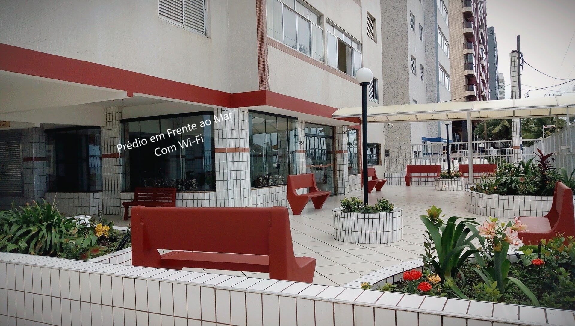 An outdoor seating area with red benches and potted plants.