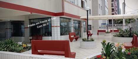 An outdoor seating area with red benches and potted plants.
