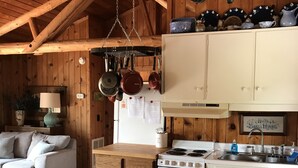 Een landelijke keuken met houten kastjes, een fornuis en hangende pannen.