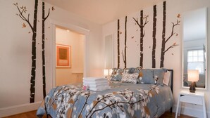 A bedroom with a bed, a nightstand, a mirror, and a door leading to another room. - Quiet Flat. Vibrant Neighborhood! Walk to Pike Place, great restaurants & more. (Seattle)
