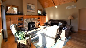 Un salon chaleureux avec une cheminée en pierre, un plafond en bois et des sièges confortables.