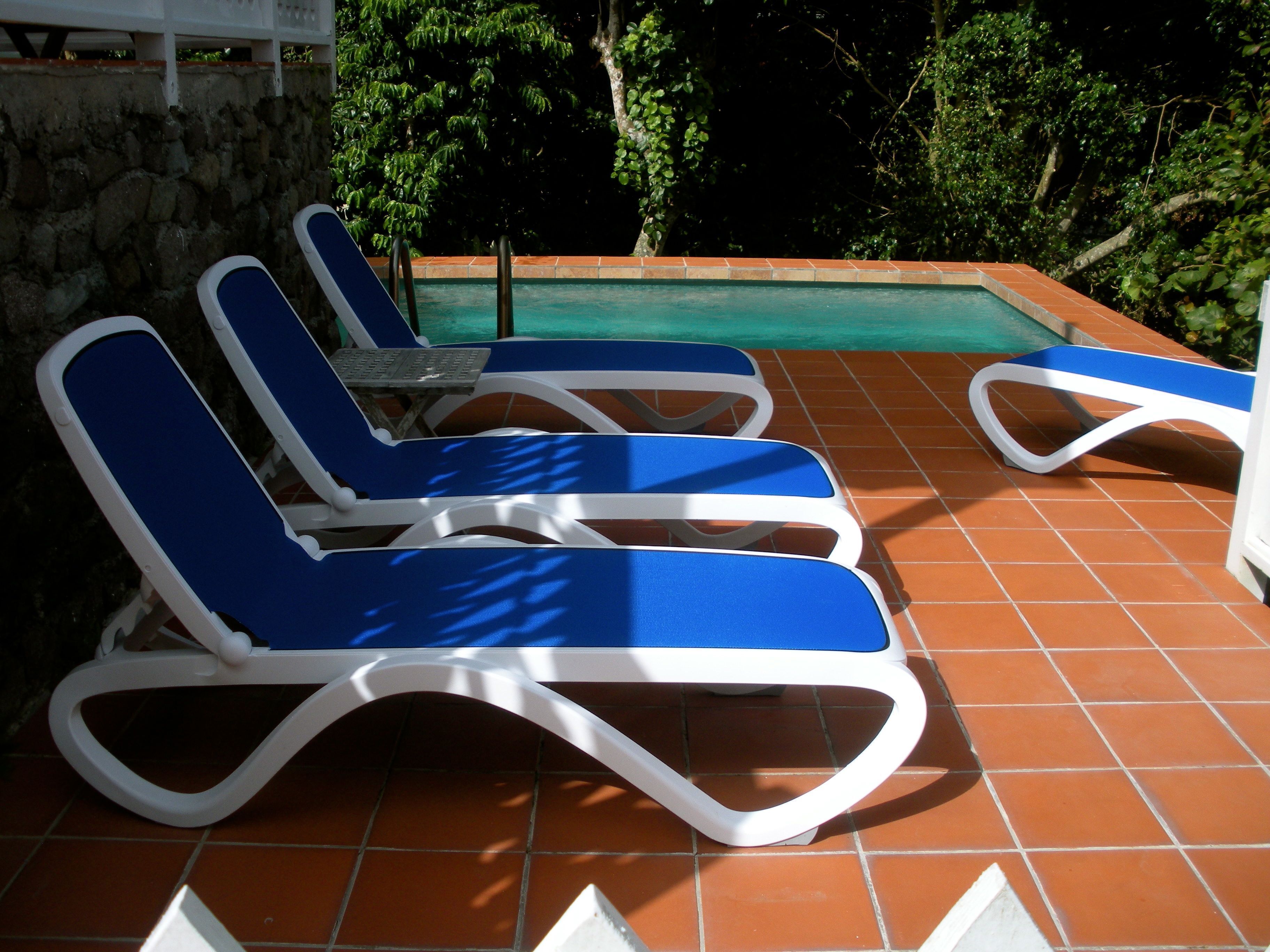 Un espace aménagé au bord de la piscine, avec des chaises longues et un mur en pierre.