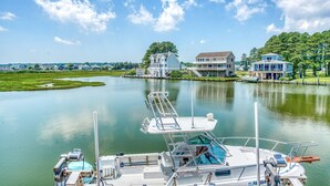 A marina with boats docked, a calm lake, and houses in the background. - Diving Duck | Waterfront Dock + Hot Tub w/ Captain's Cove Pools & Golf, Pet Friendly 5BR Retreat (Greenbackville)