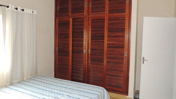 A bedroom with a bed, a wardrobe, and a door. - House 1 Suite and 2 Bedrooms - Jd. Suarão - Itanhaém (Itanhaém)