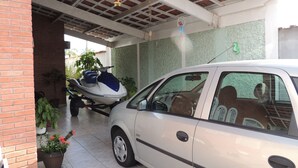 A white car parked in a covered garage with a blue and white jet ski in the background. - House 1 Suite and 2 Bedrooms - Jd. Suarão - Itanhaém (Itanhaém)