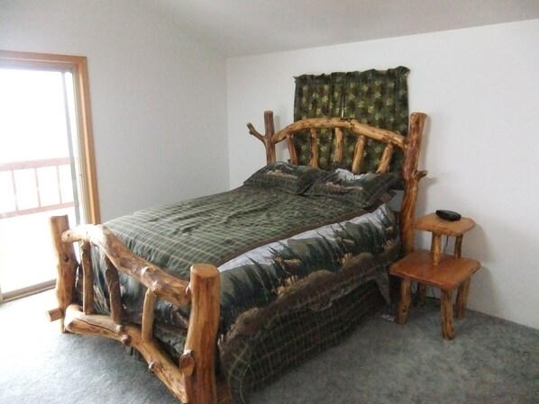 Una cama con estructura de madera y edredón verde.