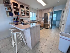 A modern kitchen with a central island, stainless steel appliances, and light wood cabinetry.