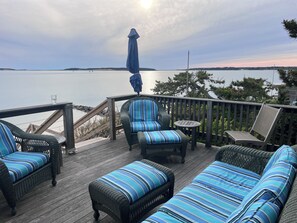 Um terraço com móveis de vime e vista para a água.