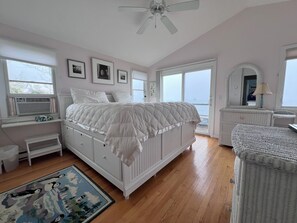 A bedroom with a bed, dresser, and a large window.
