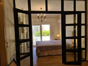 Ein Schlafzimmer mit einem großen Bett, einer Chandelüster und Blick auf Grün.