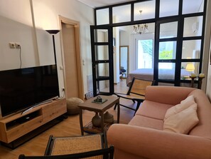 Ein modernes Wohnzimmer mit Flachbildfernseher, einer Couch, einem Couchtisch und einem Essbereich.