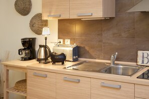 Eine moderne Küche mit Spüle aus Edelstahl, einer Kaffeemaschine, einem Toaster und einer dekorativen Lampe.