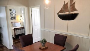 Un coin repas avec une table en bois, quatre chaises et une décoration maritime au mur.