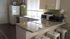 Une cuisine dotée d’un îlot central, de meubles blancs, d’un four à micro-ondes et d’un lave-vaisselle.