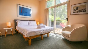 Quarto de hotel com cama, poltrona, janela e obras de arte nas paredes.