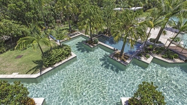 A resort with multiple swimming pools surrounded by lush greenery and palm trees.
