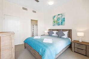 A bedroom with a bed, bedside tables, a wardrobe, and a door. - 3 Bedroom Executive Rooftop Apartment (Casuarina)