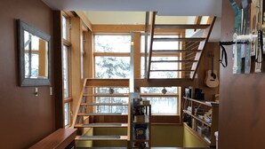 A multi-level wooden interior with a staircase, bookshelves, and a guitar.