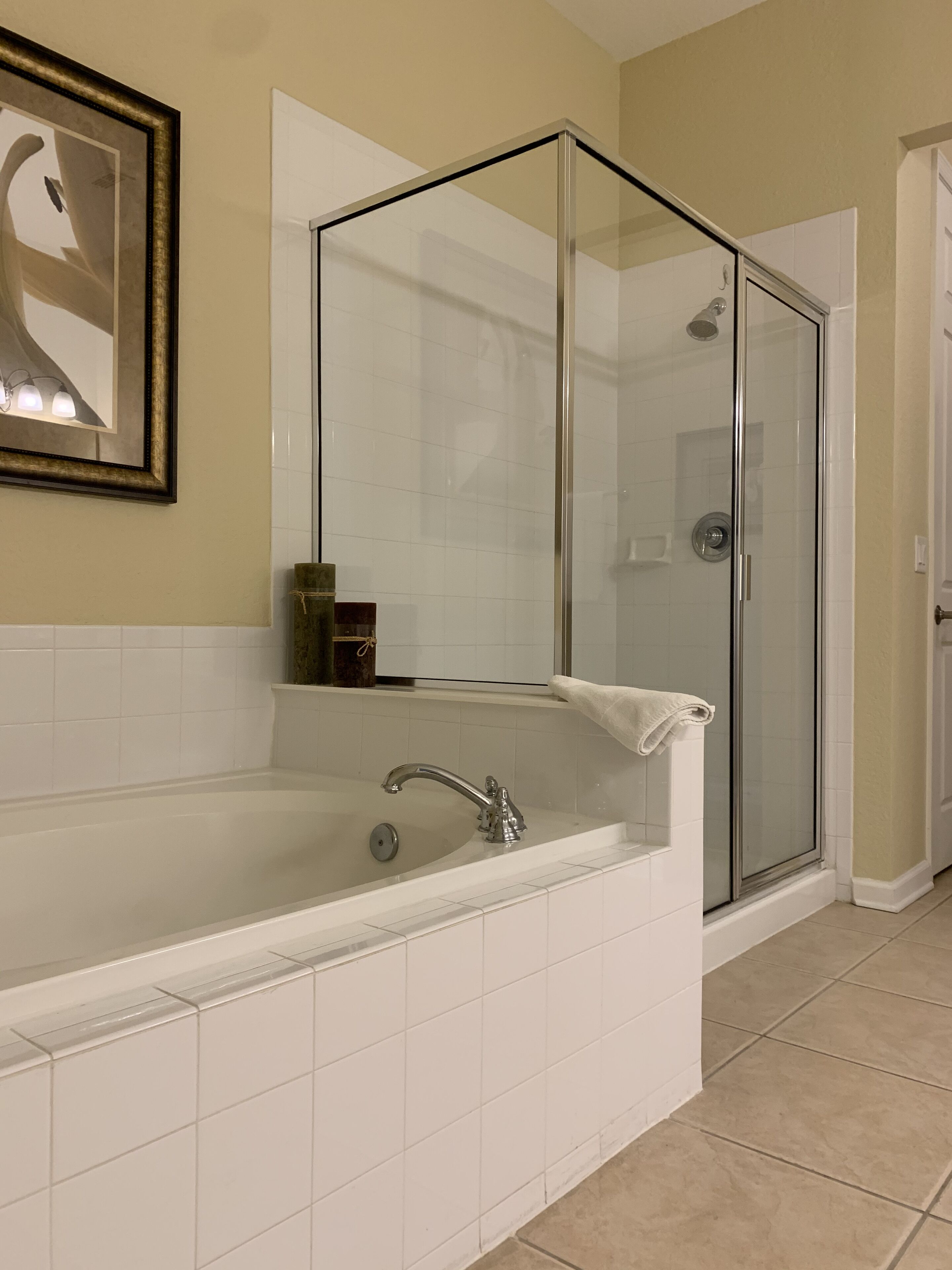 Une salle de bain moderne avec une grande baignoire, une douche à parois de verre et une œuvre d’art encadrée au mur.