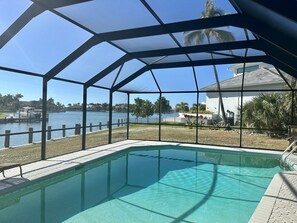 A pool with a clear view of a lake and a boat dock.