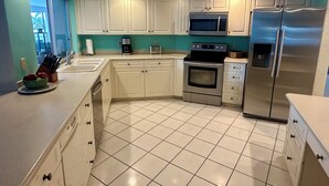 A modern kitchen with white cabinets, a stainless steel refrigerator, a microwave, and an oven. - Waterfront home with south facing pool & views over the bay (Marco Island)