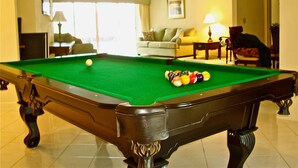 A pool table with balls, a sofa, a lamp, and a chair in a room with a tiled floor. - Waterfront home with south facing pool & views over the bay (Marco Island)