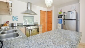 Een keuken met granieten aanrechtbladen, roestvrijstalen apparatuur, houten keukenkastjes en een magnetron.