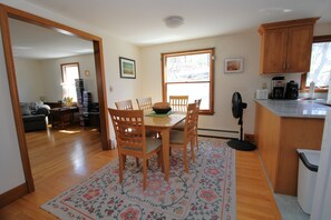 Un comedor con una mesa y sillas de madera, una cocina con armarios de madera y vistas por una ventana.