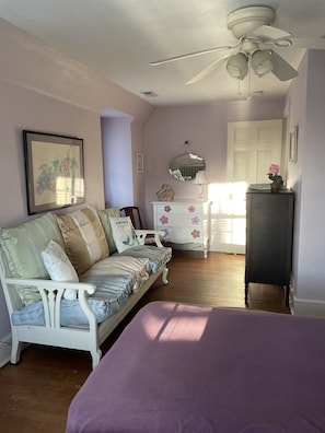 A bedroom with a white bed, a white sofa, a dresser, a ceiling fan, and a door. - Bay cottage, Beach 100 yards away! RESERVE NOW!!! (Cape Charles)