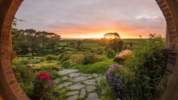 A rustic stone archway framing a lush garden with a sunset view. - Palm Court Motel (Otorohanga)